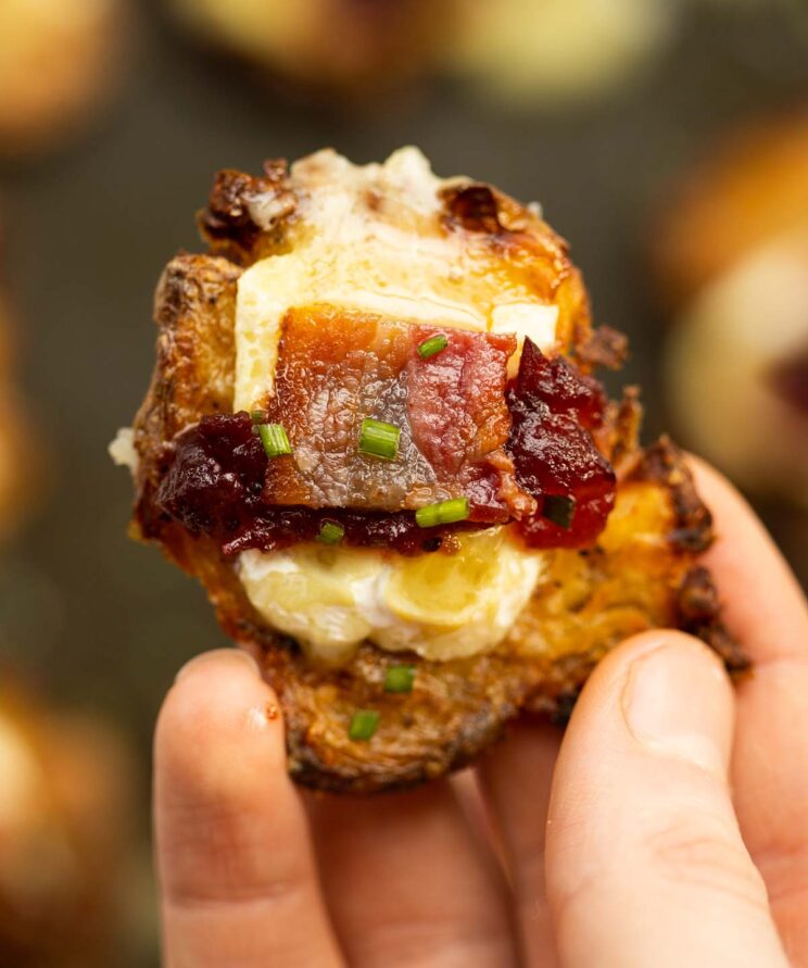 close up overhead shot of hand holding cranberry bacon brie smashed potato