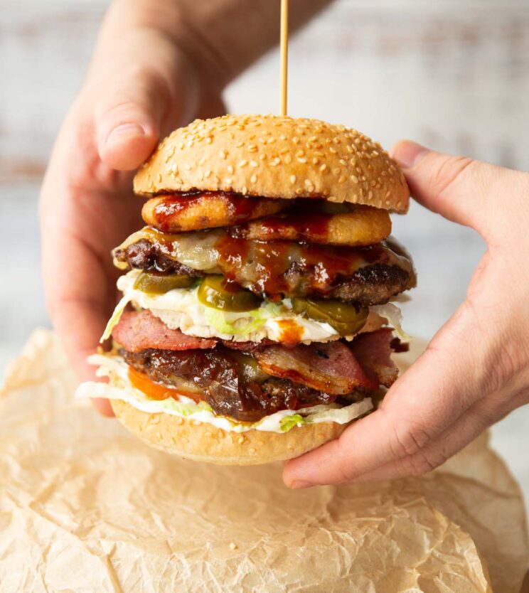 hands holding burger above brown parchment paper