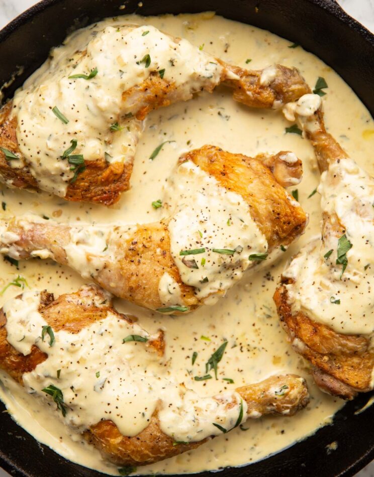 creamy dijon chicken served in cast-iron pan garnished with tarragon