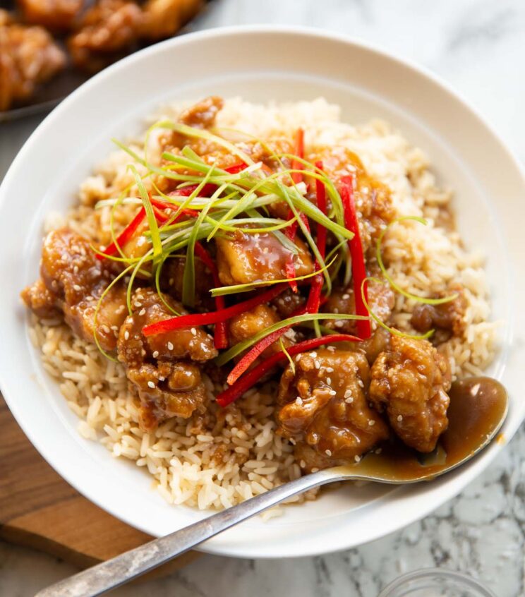 salted caramel chicken served in white bowl with rice garnished with spring onion and red chilli